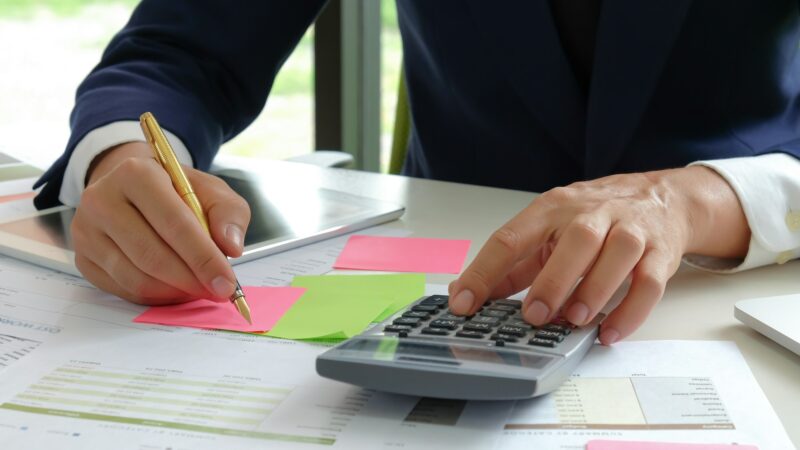 Analysts use a calculator and pen to evaluate the fluctuating stock market situation.